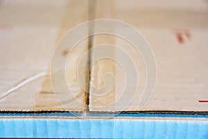 Criss crossing clear tape lines closing a white flat rate box for shipping in the mail