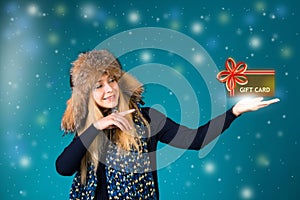 Cristmass gift card. Winter woman is pointing showing a gift card.