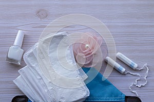 Critical days. Menstruation pads, hygiene items - pads, panty liners and white tampons on a wooden background. Hygiene Bag - Blue.