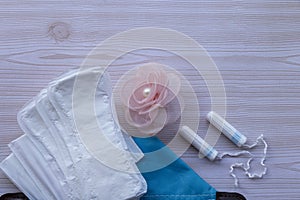 Critical days. Menstruation pads, hygiene items - pads, panty liners and white tampons on a wooden background. Hygiene Bag - Blue.