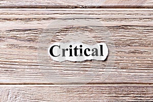 CRITICAL of the word on paper. concept. Words of CRITICAL on a wooden background