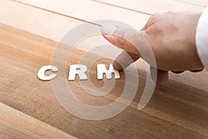 CRM word with male hand on wood table.Business marketing,analysis