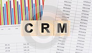 CRM word written on wood block. Faqs text on table, concept