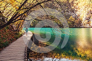 Croatia nature park Plitvice Lakes in autumn - boy walks on bridge over the lake photo