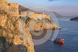 Croatia. South Dalmatia. Aerial view of Dubrovnik, medieval walled city and a read boat crossing the sea photo