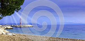 Croatian beach and Adriatic Sea with visible sun rays - Tucepi, Makarska Riviera, Croatia