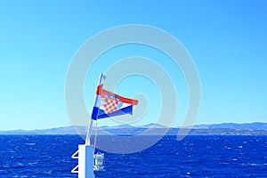 Croatian flag on wind, blue sky and Adriatic sea in background