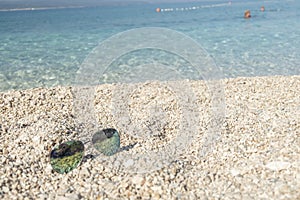 Croatian pebble beach with sunglasses