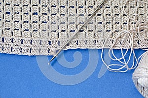 Crochet with beige cotton threads on a blue background