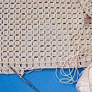 Crochet with beige cotton threads on a blue background