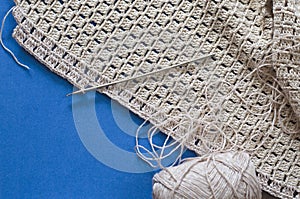 Crochet with beige cotton threads on a blue background