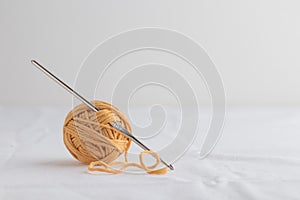 Crochet hook and a small ball of yellow yarn