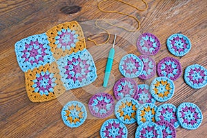 Crochet patterns in turosque, lilac and yellow colors, crochet tricot hook and a yellow thread layed out on scratched wooden