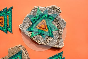 Crochet triangle motifs placed to set shape on piece of palm bark with an orange surface underneath.