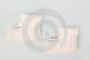 Crochet white baby booties, on a gray background,