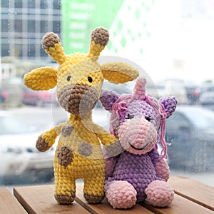 Crocheted amigurumi yellow giraffe and unicorn. Knitted handmade toy