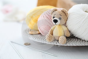 Crocheted bear and knitting supplies on white wooden table. Engaging in hobby