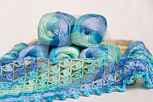 Crocheting in blue and green tones and skeins piled together