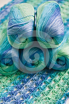 Crocheting in blue and green tones and skeins piled together