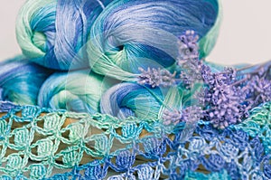 Crocheting in blue and green tones and skeins piled together