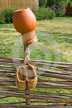 Crock and bast shoes on wicker fence