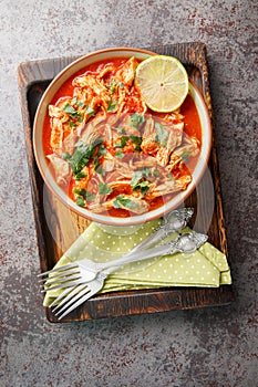 Crock pot chicken tomato salsa with taco seasoning and lime close-up in a bowl on a wooden board. Vertical top view