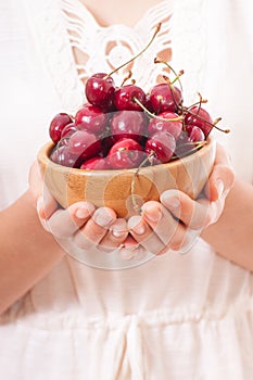 Crockery with cherries in woman hands.