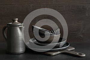 Crockery, clayware, dark utensils and stuff on dark tabletop. Kitchen still life photo