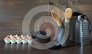 Crockery, clayware, dark utensils and other different stuff on wooden tabletop. Kitchen still life as background for design. Copy photo