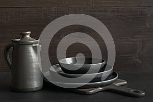 Crockery, clayware, dark utensils and stuff on dark tabletop. Kitchen still life photo