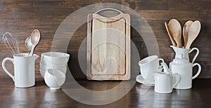 Crockery, clayware, white utensils and other different stuff on wooden tabletop. Kitchen still life as background for design. Copy