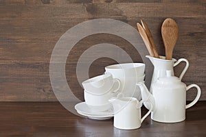 Crockery, clayware, white utensils and other different stuff on wooden tabletop. Kitchen still life as background for design. Copy