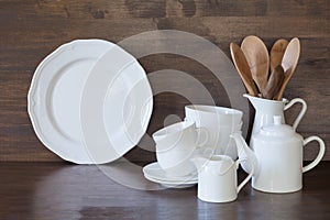 Crockery, clayware, white utensils and other different stuff on wooden tabletop. Kitchen still life as background for design. Copy