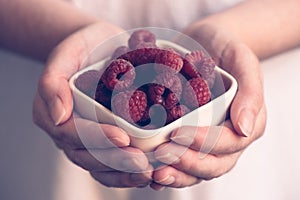 Crockery with raspberries in woman hands