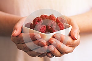 Crockery with raspberries in woman hands