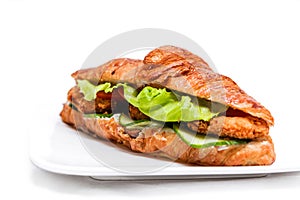 Croissant with chicken cutlet, fresh cucumber, tomato and lettuce on a white background.
