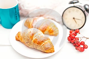 Croissant and coffee as breakfast in bed on an early Sunday