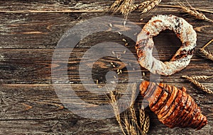 Croissant and cracknel on old wooden background. Concept of pastry, vintage style, top view photo