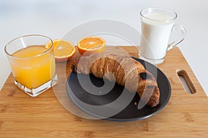Croissant and fresh squeezed orange juice and milk on wooden table