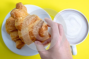 Croissant and hot cocoa or hot chocolate on a yellow background, top view,breakfast