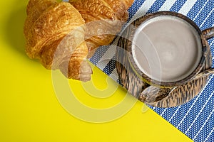 Croissant and hot cocoa or hot chocolate on a yellow background, top view,breakfast