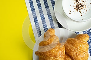 Croissant and hot milk on a yellow background, top view,breakfast