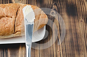 Croissant and a knife with butter on a wooden table.Top view, copyspace. French breakfast