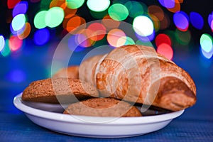 Croissant and oat cookies on white plate. Winter holiday tradition. Sweets for Santa Claus and his helpers. Santa treats