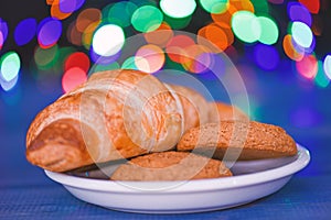 Croissant and oat cookies on white plate. Winter holiday tradition. Sweets for Santa Claus and his helpers. Santa treats