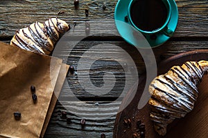 Croissant in a paper bag with a cup of coffee. Breakfast, snack, food