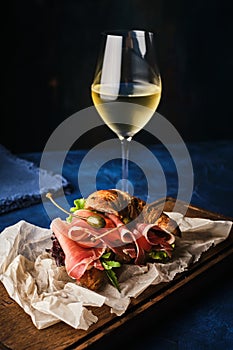 Croissant with prosciutto and herbs on a wooden board, blue background