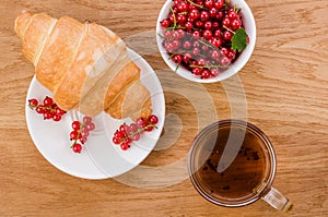 Croissant with red berries and a glass of tea/croissant with red berries and a glass of tea. Top view