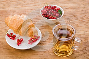 Croissant with red berries and a glass of tea/croissant with red berries and a glass of tea on a wooden background