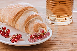 Croissant with red berries and glass with tea/croissant with red berries in white bowl and glass with tea. Toned